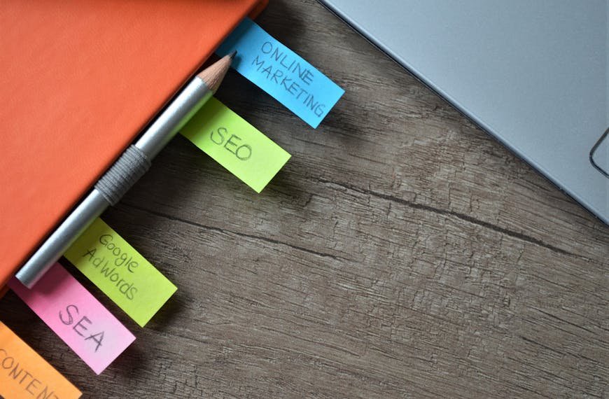 Close-up of SEO strategy planner with colorful sticky notes and a pencil on a notebook.