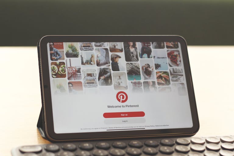 Tablet showing Pinterest homepage on a modern desk setup with a keyboard.
